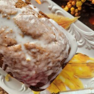 pumpkin bread with pumpkin bread icing drizzled on top on white dish