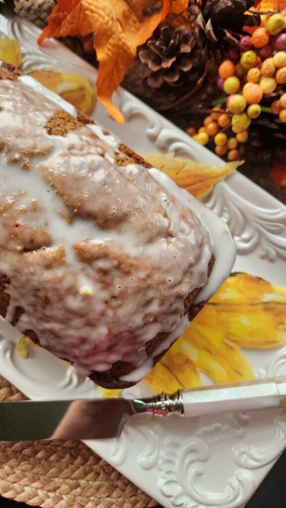 pumpkin bread with pumpkin bread icing drizzled on top on white dish