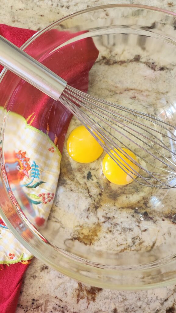 glass mixing bowl with two eggs in it