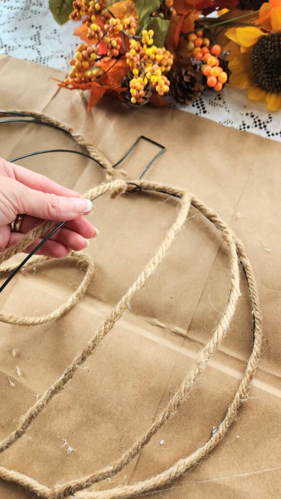 jute rope being glued to wire pumpkin frame for wreath