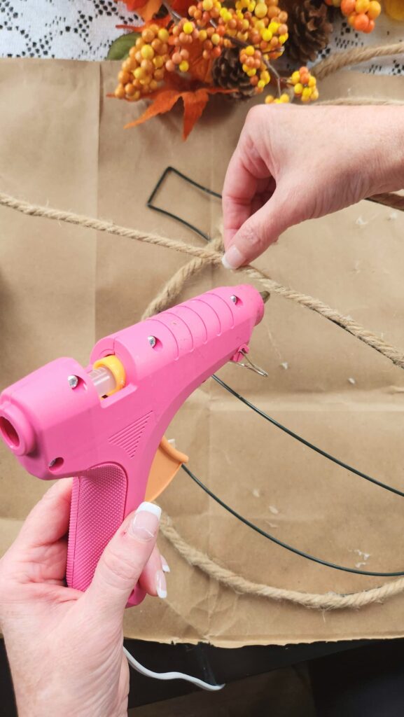 overhead photo of glue gun and jute rope being glued to wire frame