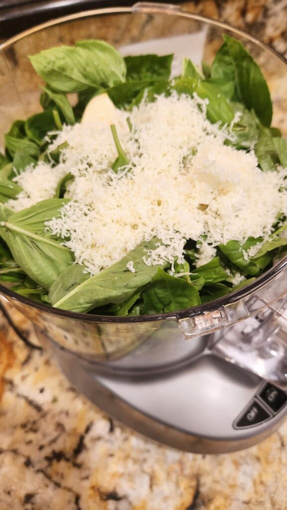 glass bowl full of basil with parmesan cheese shredded on top