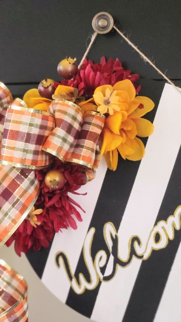 yellow, red and orange faux flowers with colorful fall plaid ribbon hung on hook