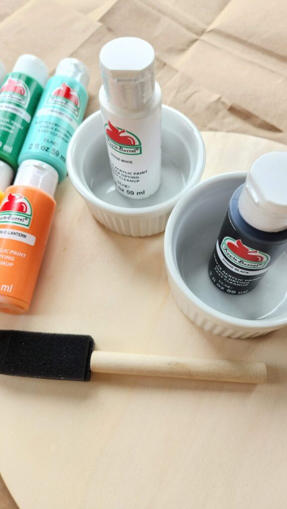 acrylic paint bottles in cups with paint brush on the side