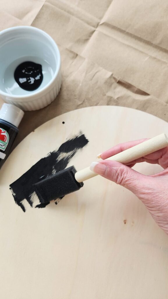 round wooden door hanger being painted black