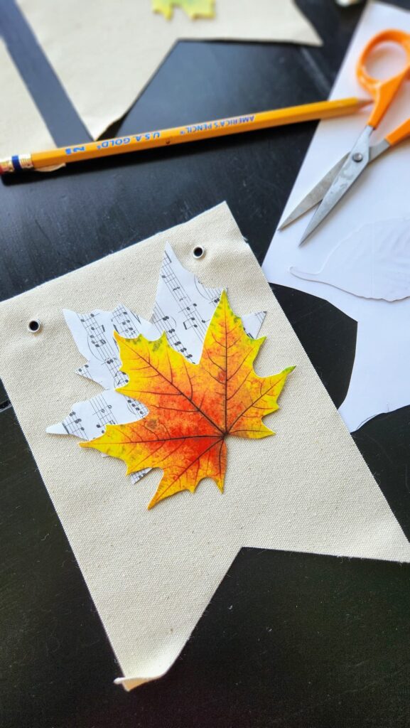 single leaf on top of cut out music sheet in shape of leaf
