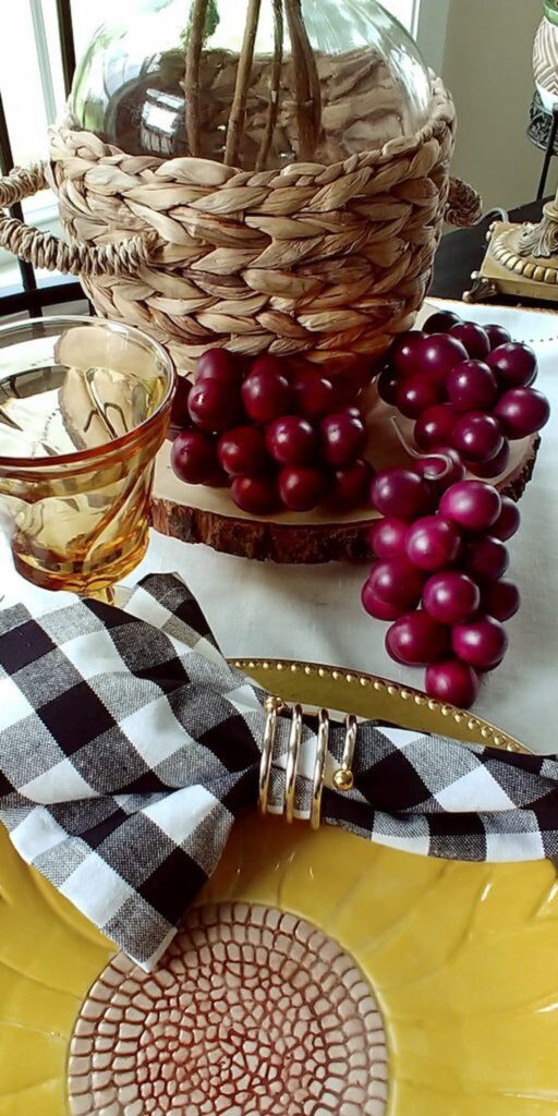 close up of wooden grapes and wicker wrapped jug on table top