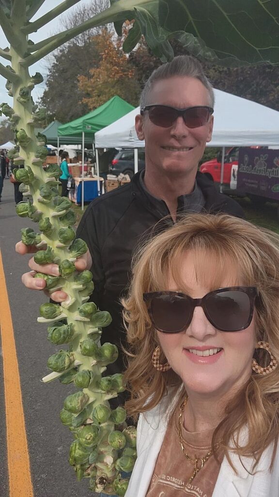 Andrew and I at farmers market with a large stalk of brussel sprouts in hand