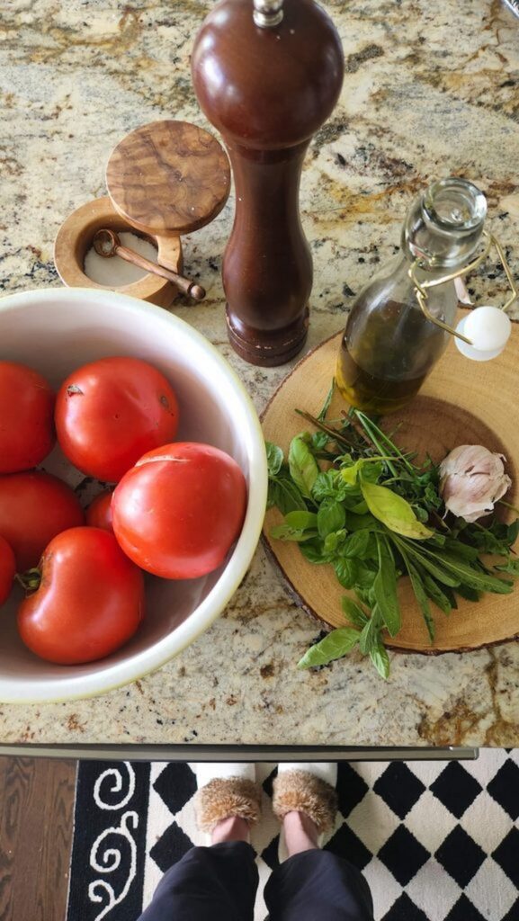 fresh tomatoes in bowl with herbs on side 