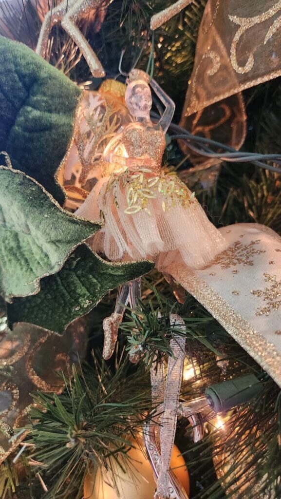 gold and glass ballerina ornament hanging on a christmas tree