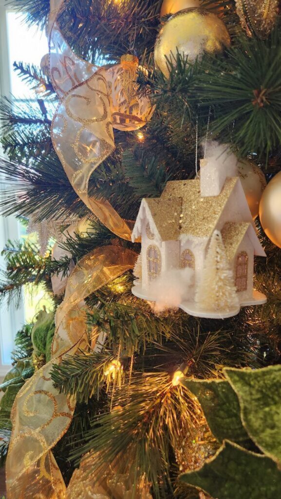 ivory tiny housee with gold glitter roof ornament hanging on a christmas tree