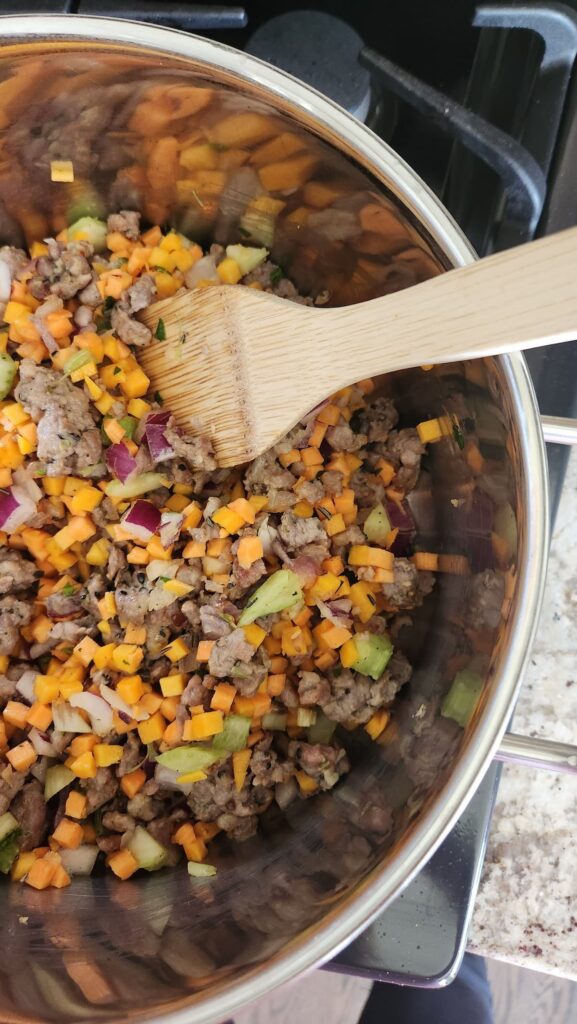 stock pot with holiday hash veggies, sausage, onion being sauteed