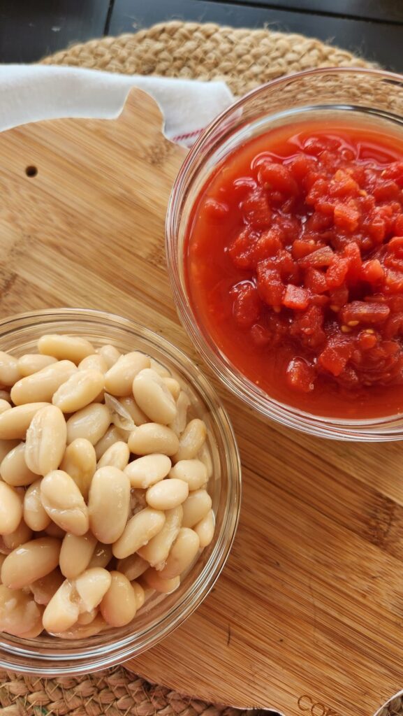 glass bowl of white beans and a glass jar of diced tomatoes