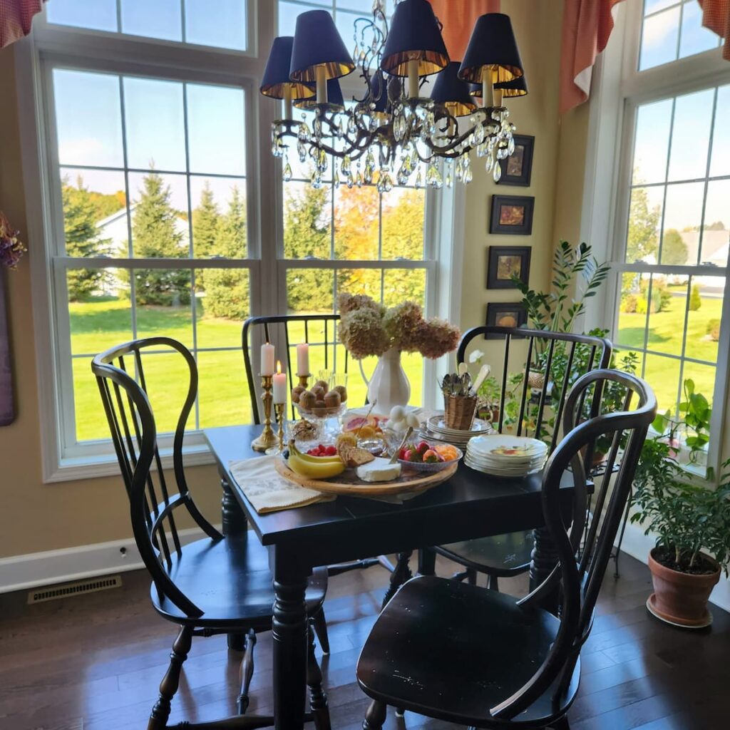 view of breakfast room with a breakfast charcuterie board on top with many breakfast foods and candles lit