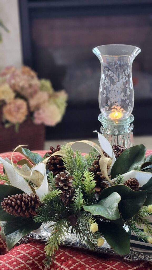 vintage hurricane lamp with greenery on fabric ottoman and tray