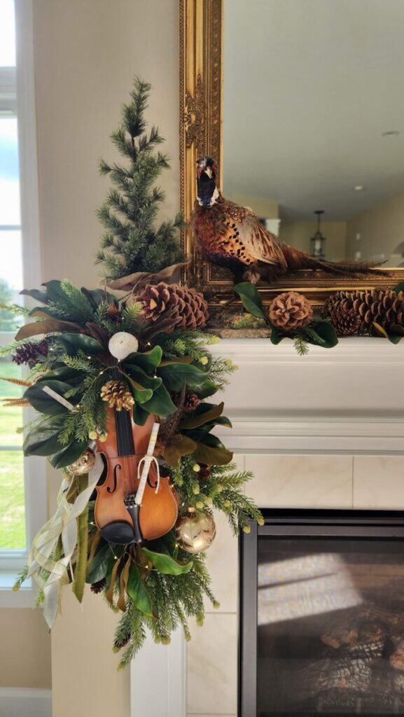 cream and green christmas decorations on mantle with pheasant and violin hanging from mantel