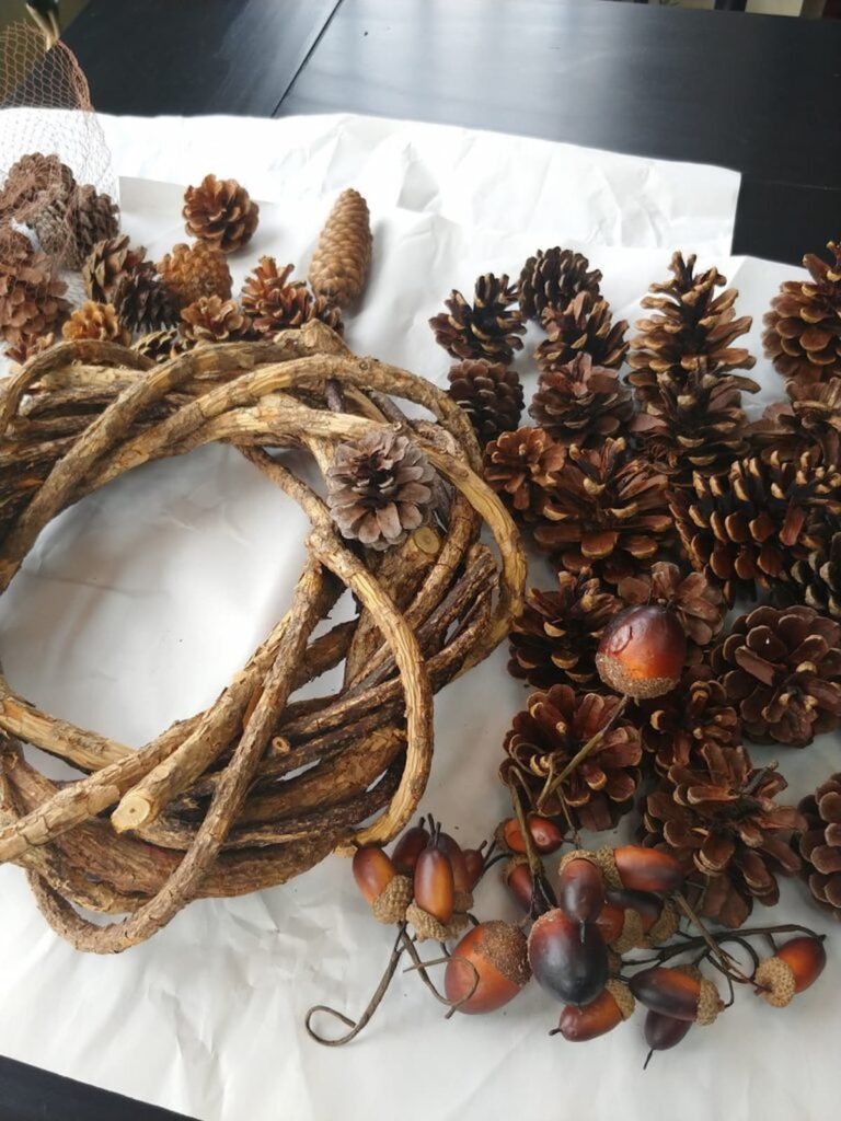 grapevine wreath with pile of pinecones next to it on table