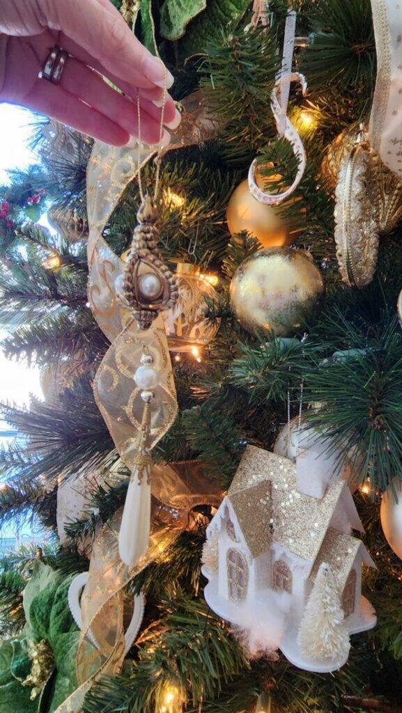 hanging a pearl and gold long ornament on christmas tree