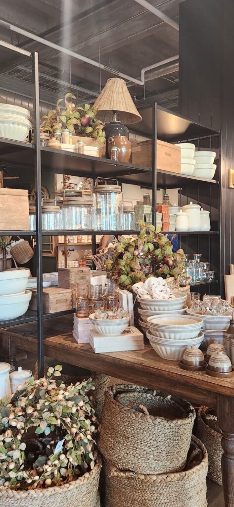 magnolia market with table of home decor items, white bowls and wicker baskets