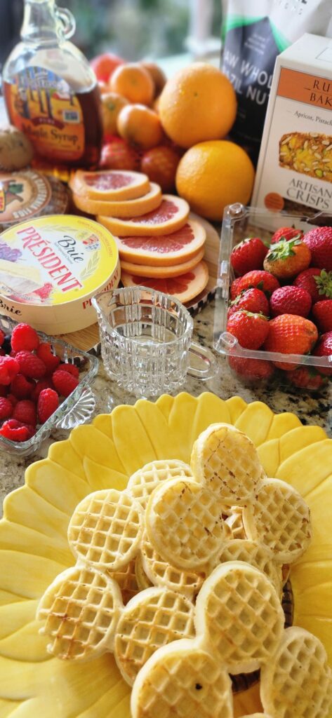 breakfast ingredients for a charcuterie breakfast board, strawberries, mini waffles, syrup