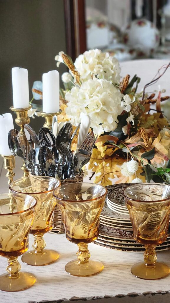 vintage silverware in a wicker basket with amber goblets in front on a table for thanksgiving