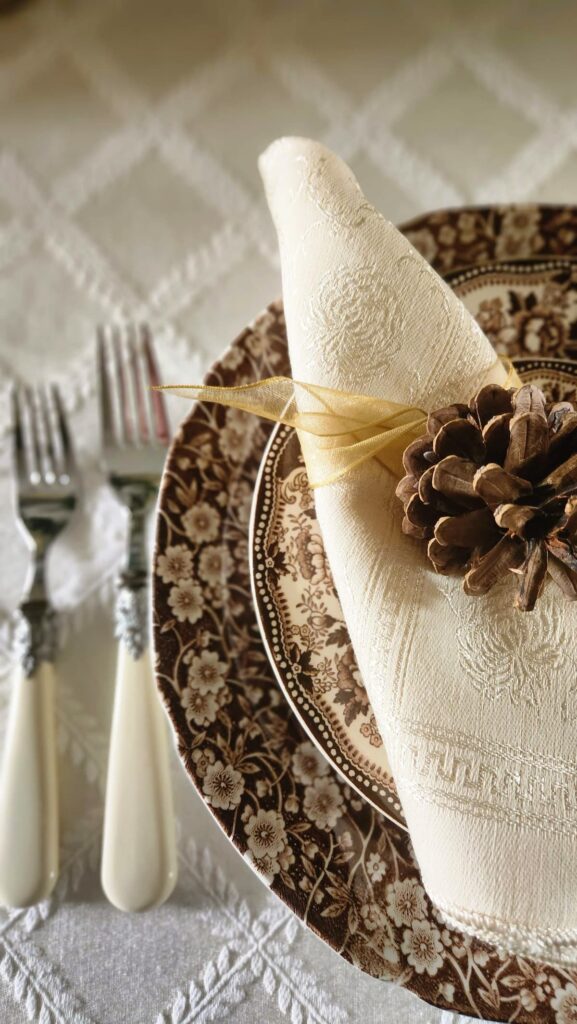 brown calico dishes with pinecone decorated on top of napkin
