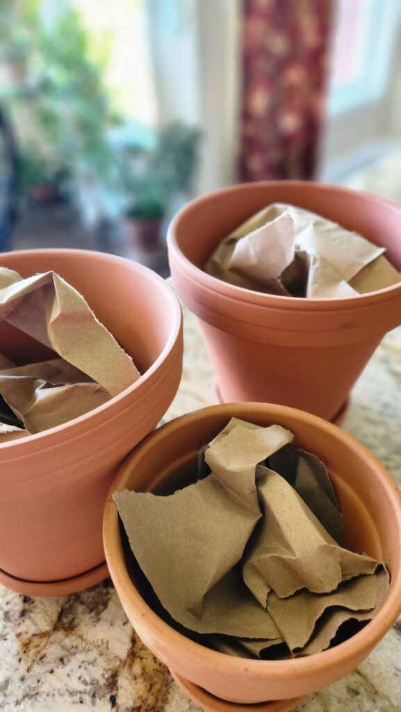 clay pots with pieces of brown paper bags stuffed in them for filling