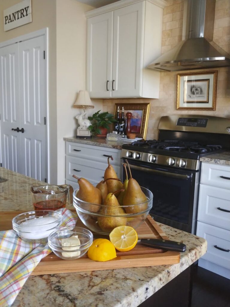 glass bowl of pears on kitchen counter with ingredients to bake pears