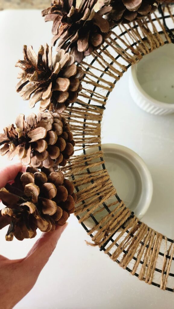 pine cones being added all the way around the wreath form