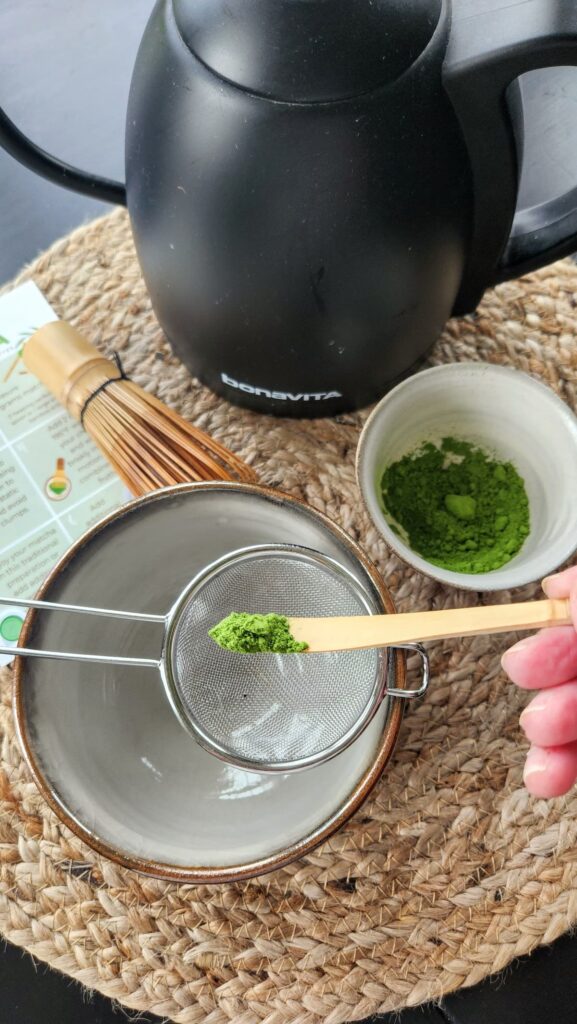 a scoop of matcha being added to the bowl