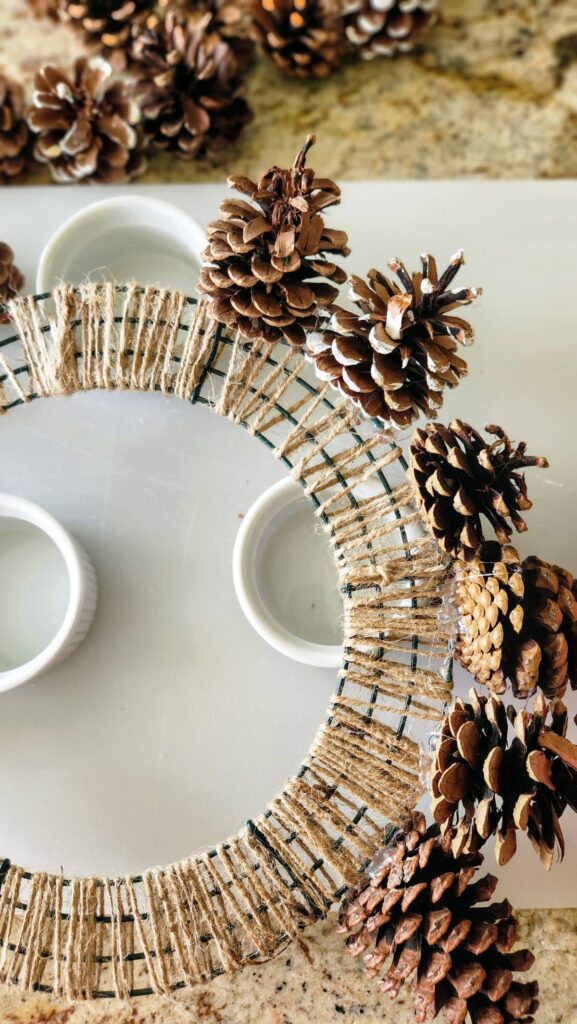 large pine cones being added to the outer wire of the wreath frame