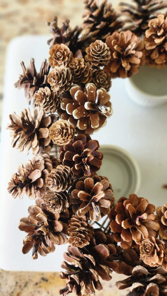 close up view of the smallest pinecones being added to the wreath filling in the spaces