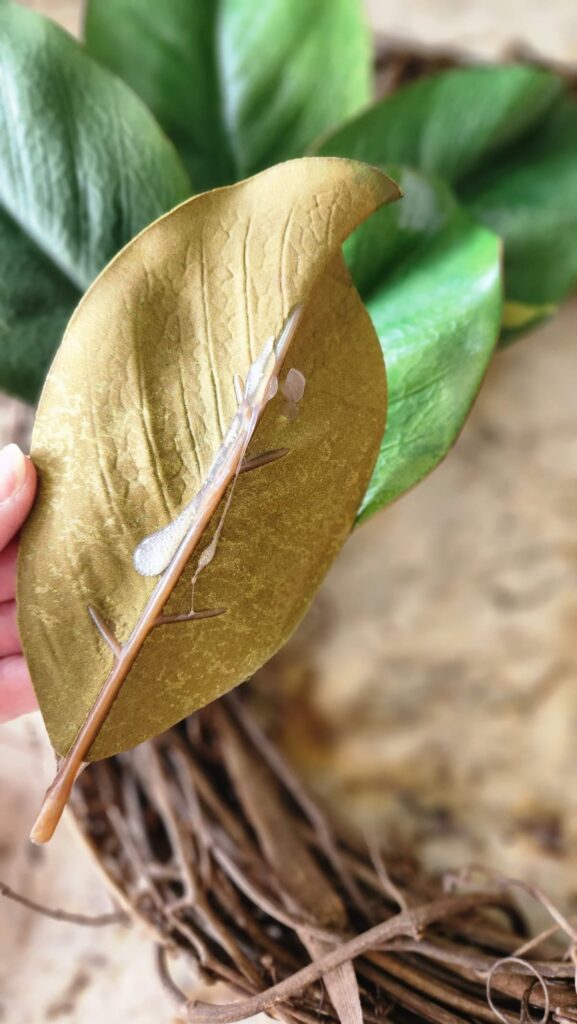 back of a faux magnolia leaf with a strip of hot glue on it