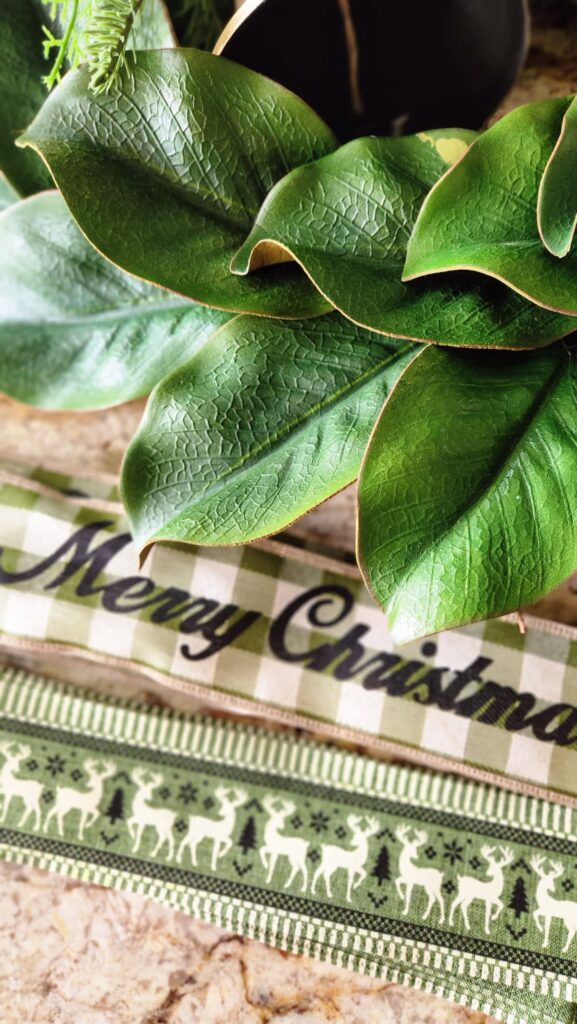 two wired ribbons in green, one with reindeer and one with merry christmas on it