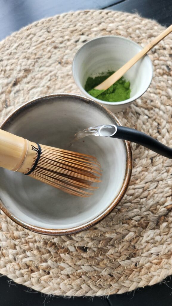 warm water being poured into a matcha bowl to heat the chasen and the bowl