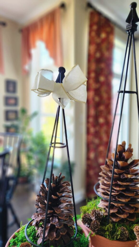 two oversized pinecones in center of pot and wire topiary frame over the top of the pinecone