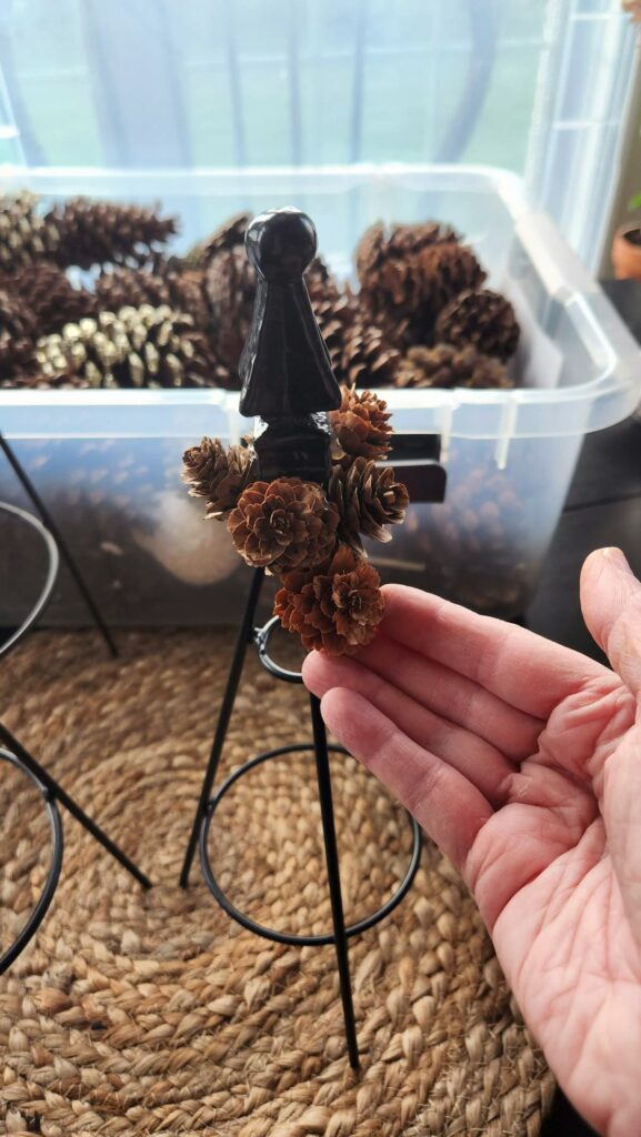 pinecones being added to top of the topiary tree form