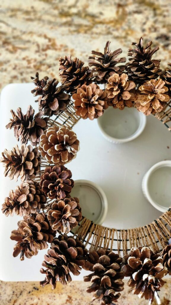 overhead view of the second row of medium sized pinecones being added to the wreath form