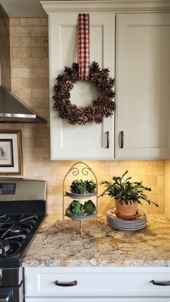 pine cone wreath hanging from kitchen cabinet door by a ribbon