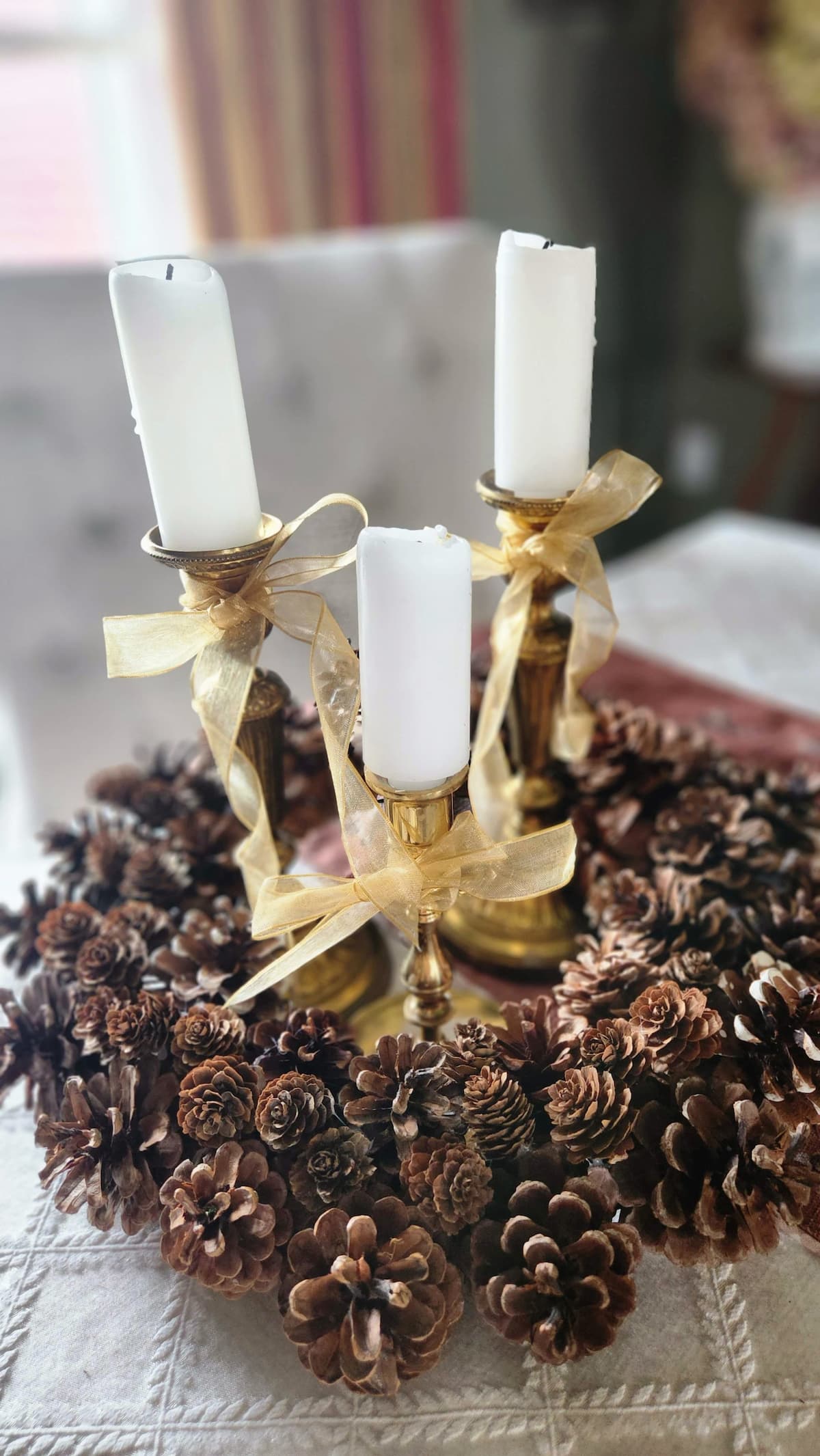 pine cone wreath on table with candlesticks and candles in the middle of the wreath