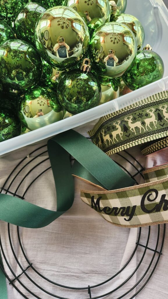 bin of green ornaments, ribbon, wire wreath frame