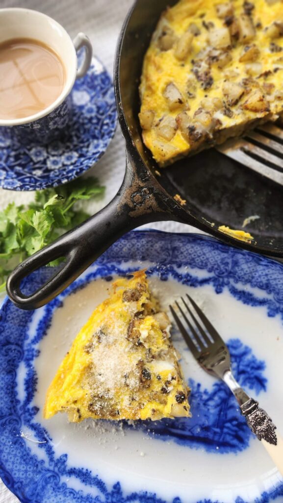 potatoe and egg frittata slice with skillet next to blue dish