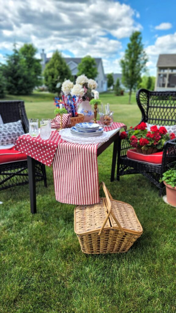 black wicker furniture in yard with picnic basket and table set next to chairs
