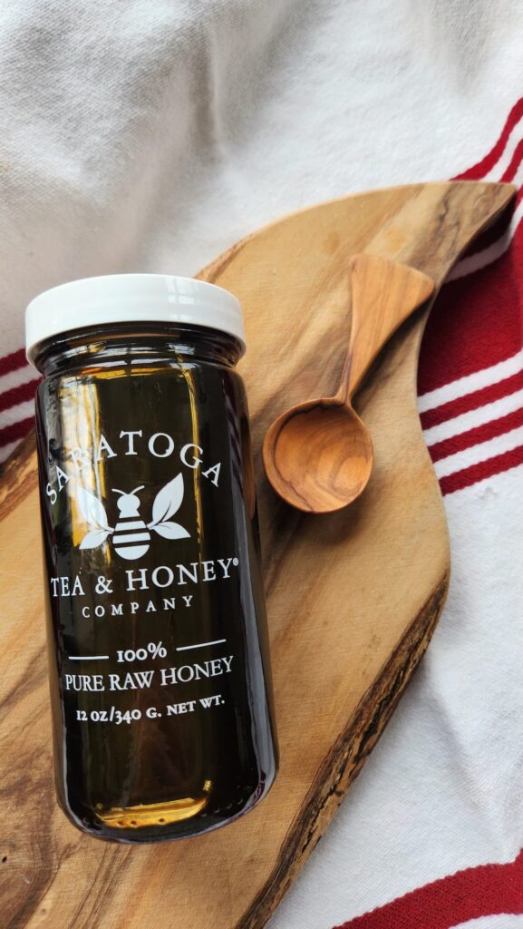 jar of buckwheat honey on its side with wooden spoon next to it