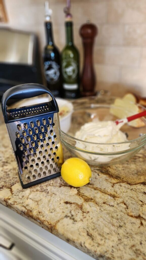 grater with fresh lemon and ricotta cheese in glass bowl
