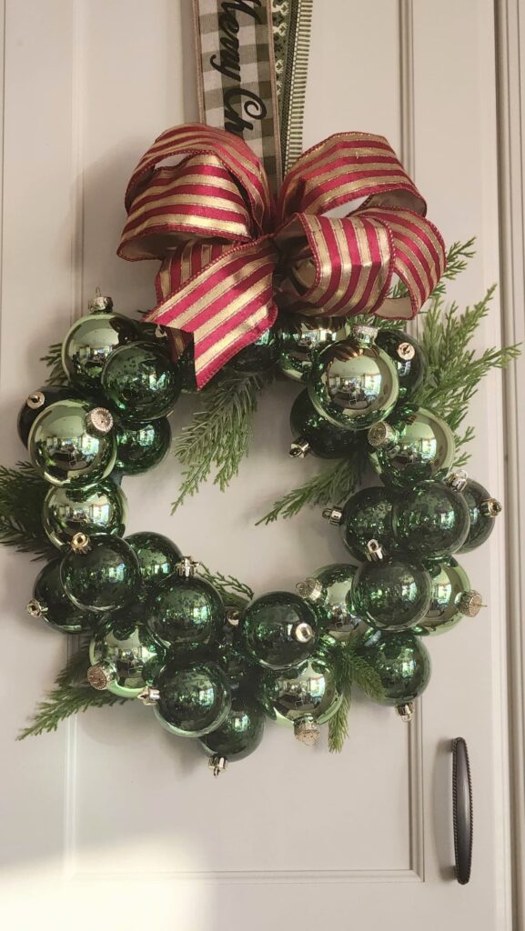 Christmas ornament wreath hung to cabinet by ribbon taped to the back of the door