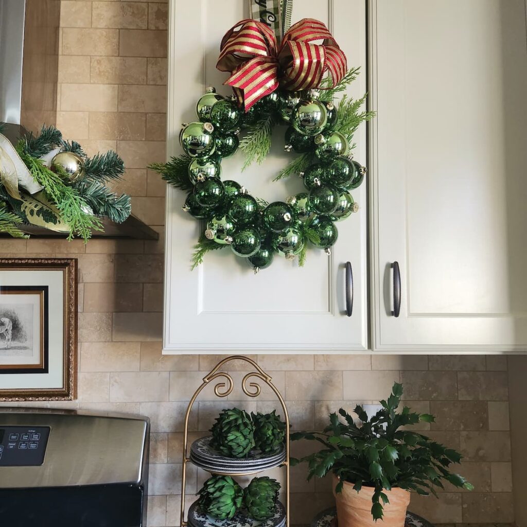 green ornament wreath hanging on kitchen cabinet