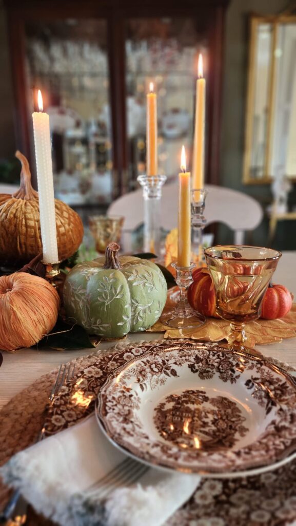 fall table with green wooden pumpkin and candles