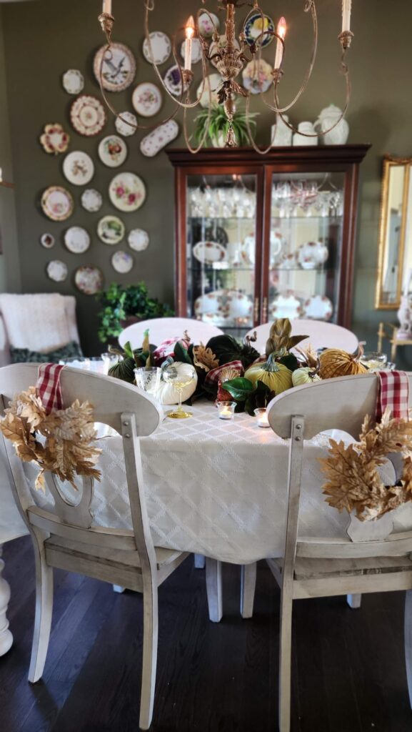 fall table with velvet green pumpkins and gold leaf wreaths on back of chairs
