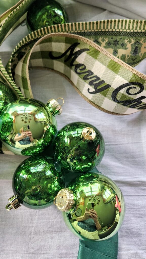 green ball ornaments being glued to the wire wreath frame